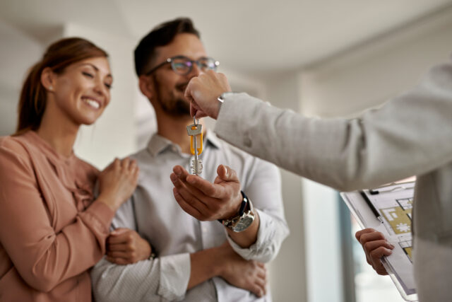 Close up of real estate agent giving new house keys to a couple.